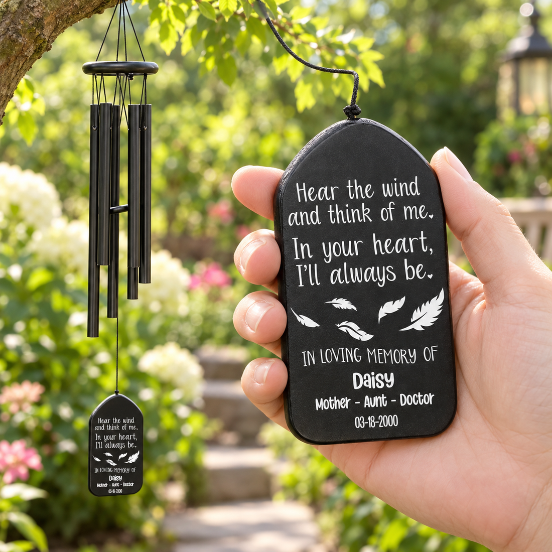 Hand holding a personalized memorial wind chime with engraved tag in a garden