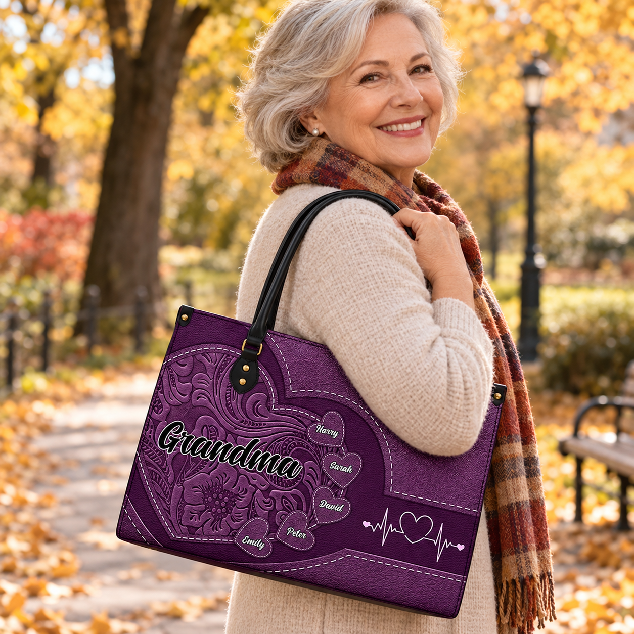 Smiling grandmother carrying a personalized leather handbag with kids' names in an autumn park