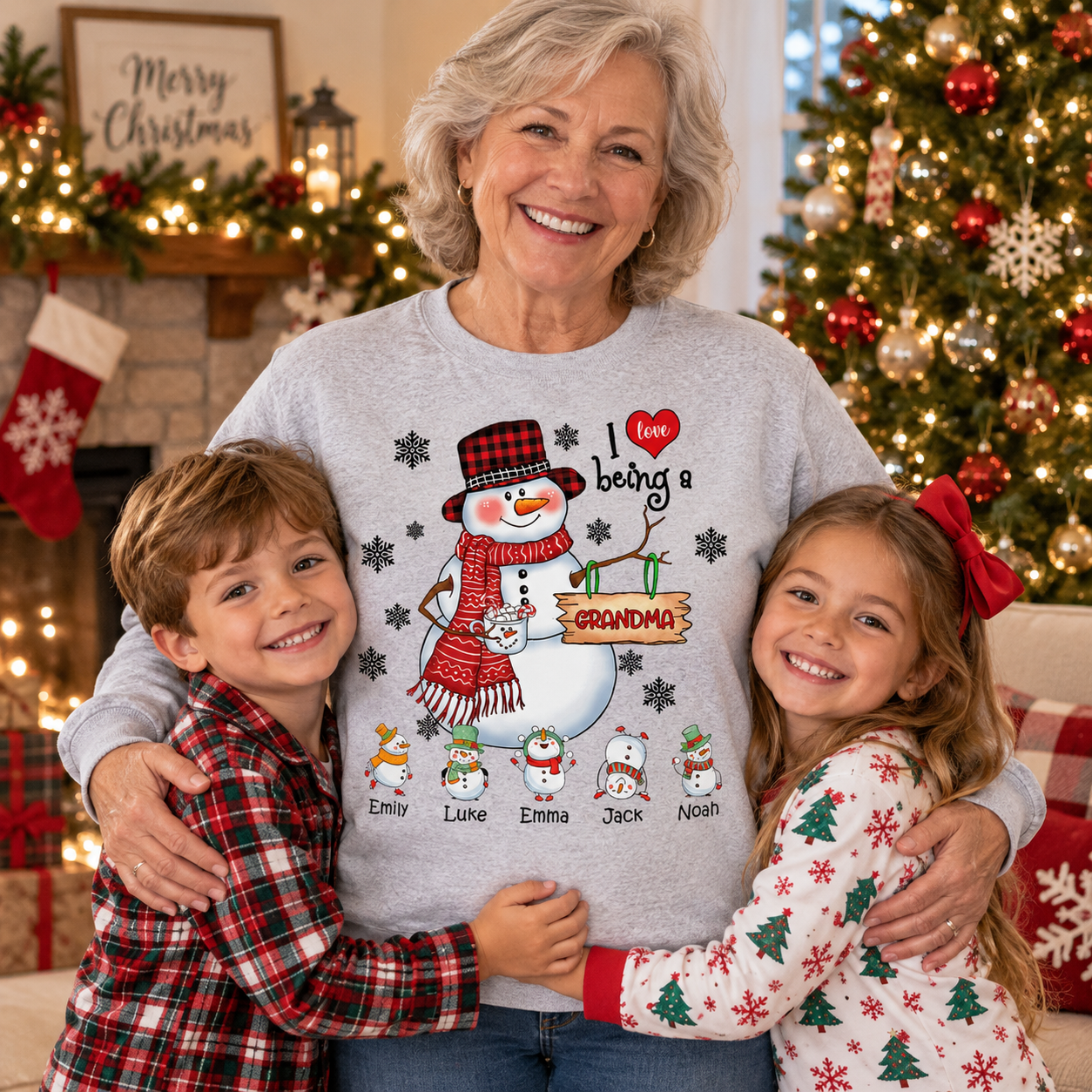 Smiling grandma in a gray snowman I love being a Grandma sweatshirt hugging two grandkids by a Christmas tree