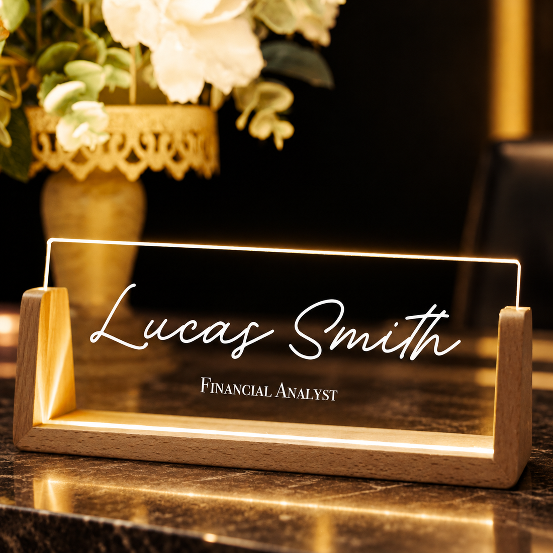 Custom lighted name desk plate glowing warmly on a reception desk, close-up
