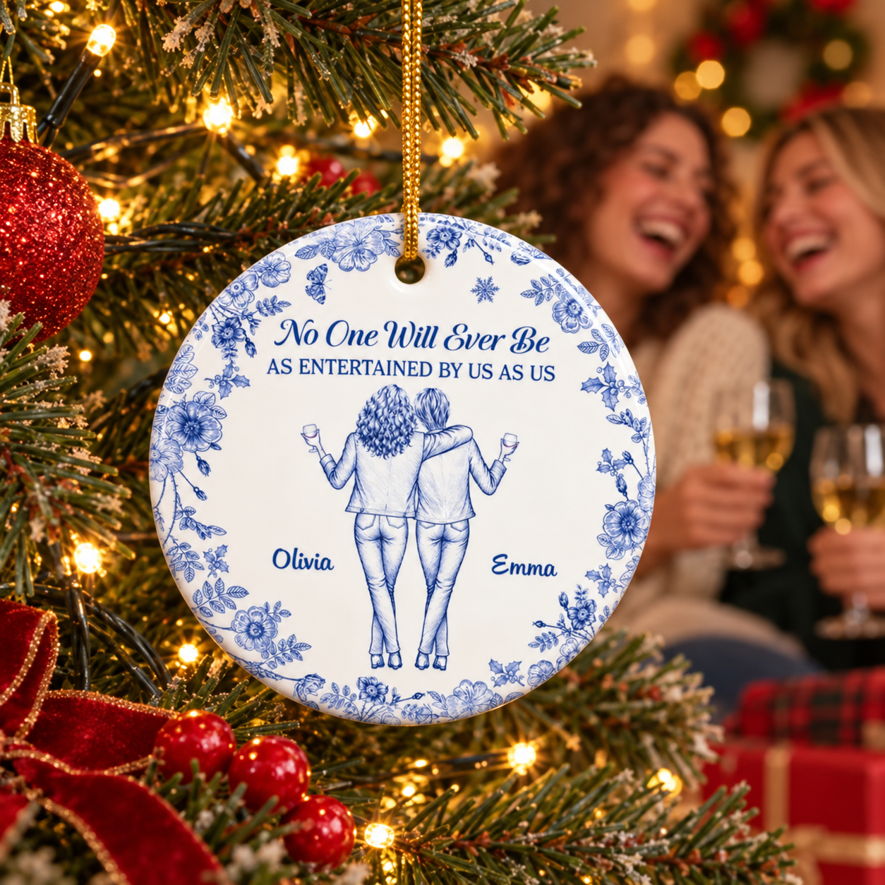 Personalized blue floral bestie ceramic ornament with names Olivia and Emma on a Christmas tree with laughing friends