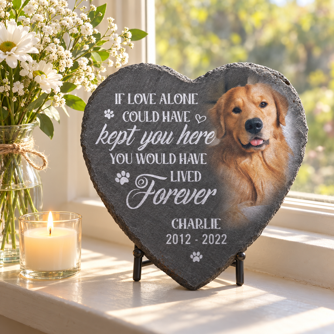 Personalized pet memorial heart stone with golden retriever photo and name Charlie on a windowsill with flowers and a candle