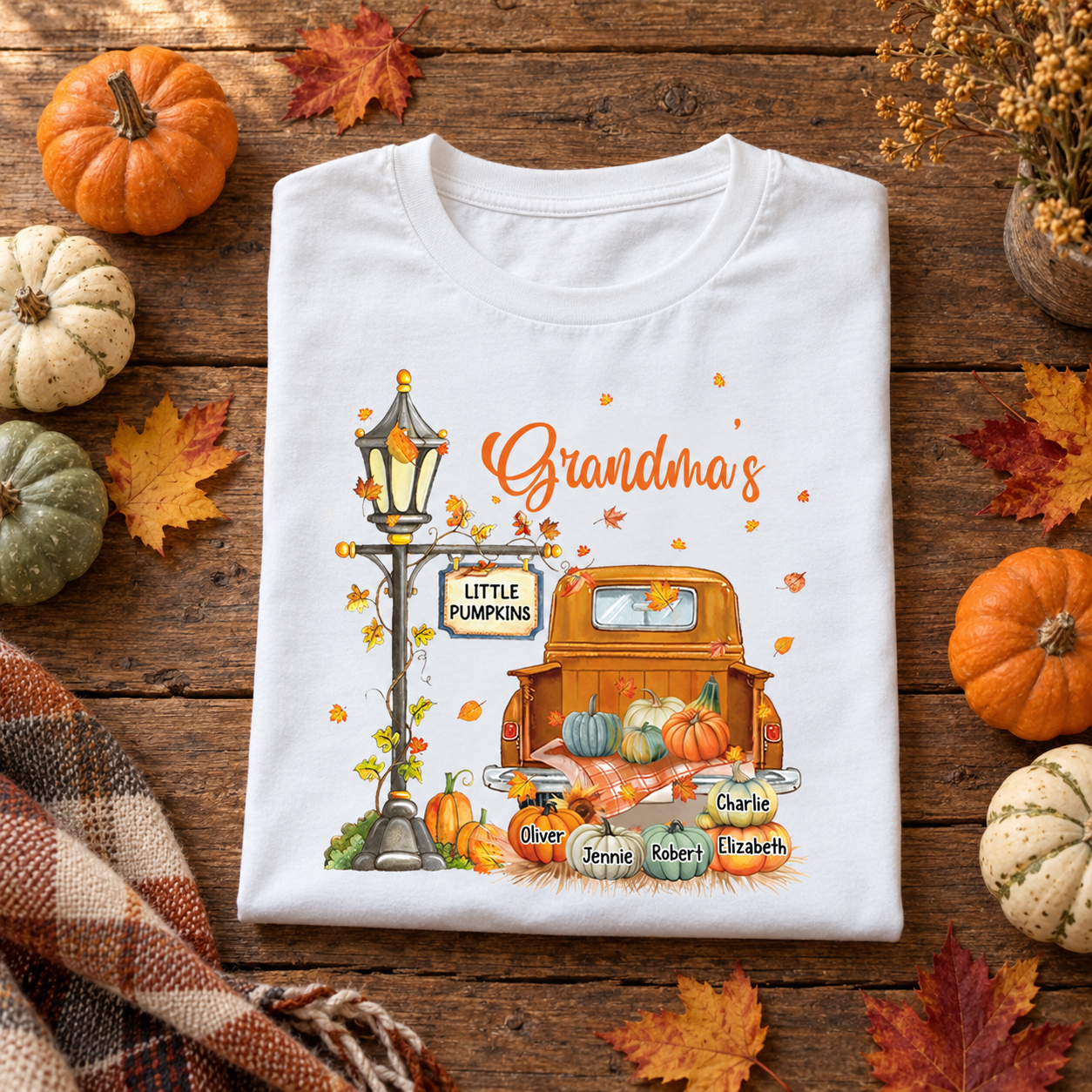 White Grandma's Little Pumpkins truck t-shirt folded on a wooden table with mini pumpkins
