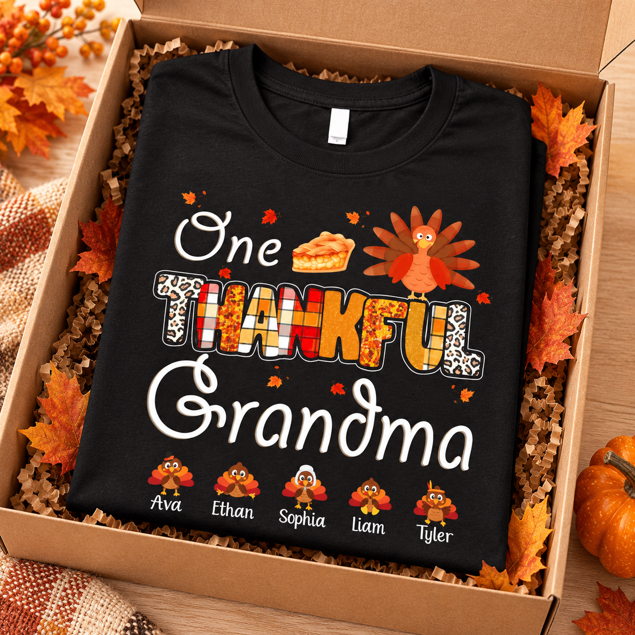 Black One Thankful Grandma personalized turkey T-shirt folded in a gift box with autumn leaves