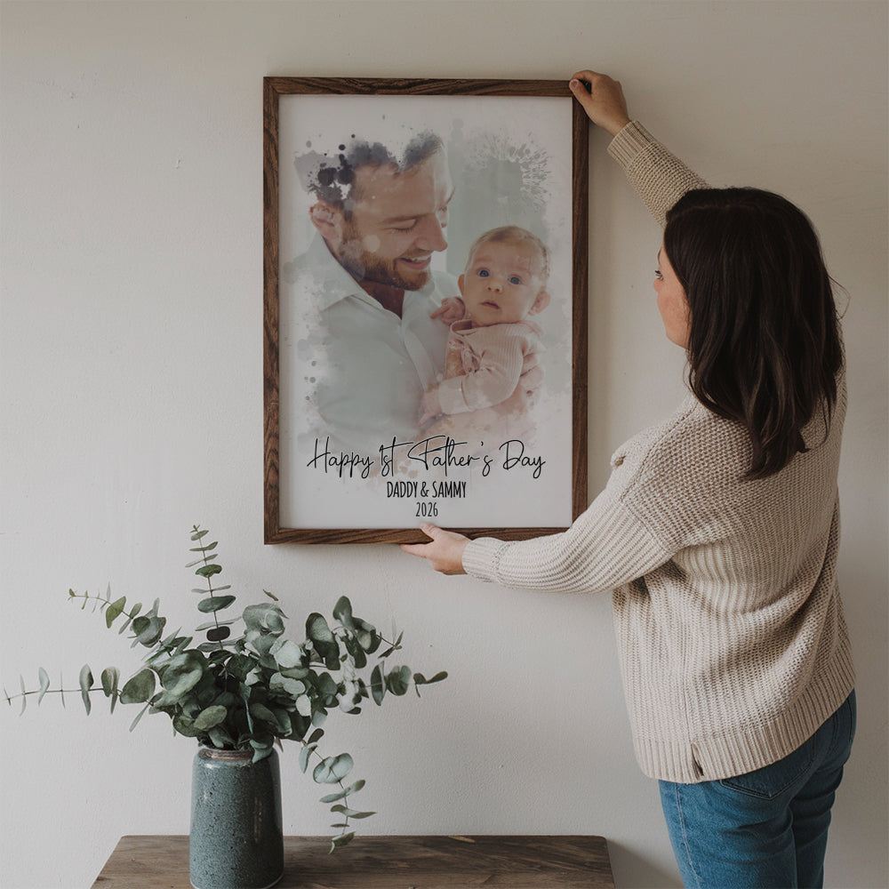 Custom Photo Watercolor First Father's Day poster, a woman hanging the framed print on a wall