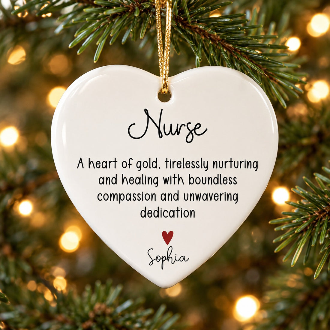 Personalized nurse heart ceramic ornament hanging on a Christmas tree branch with warm lights