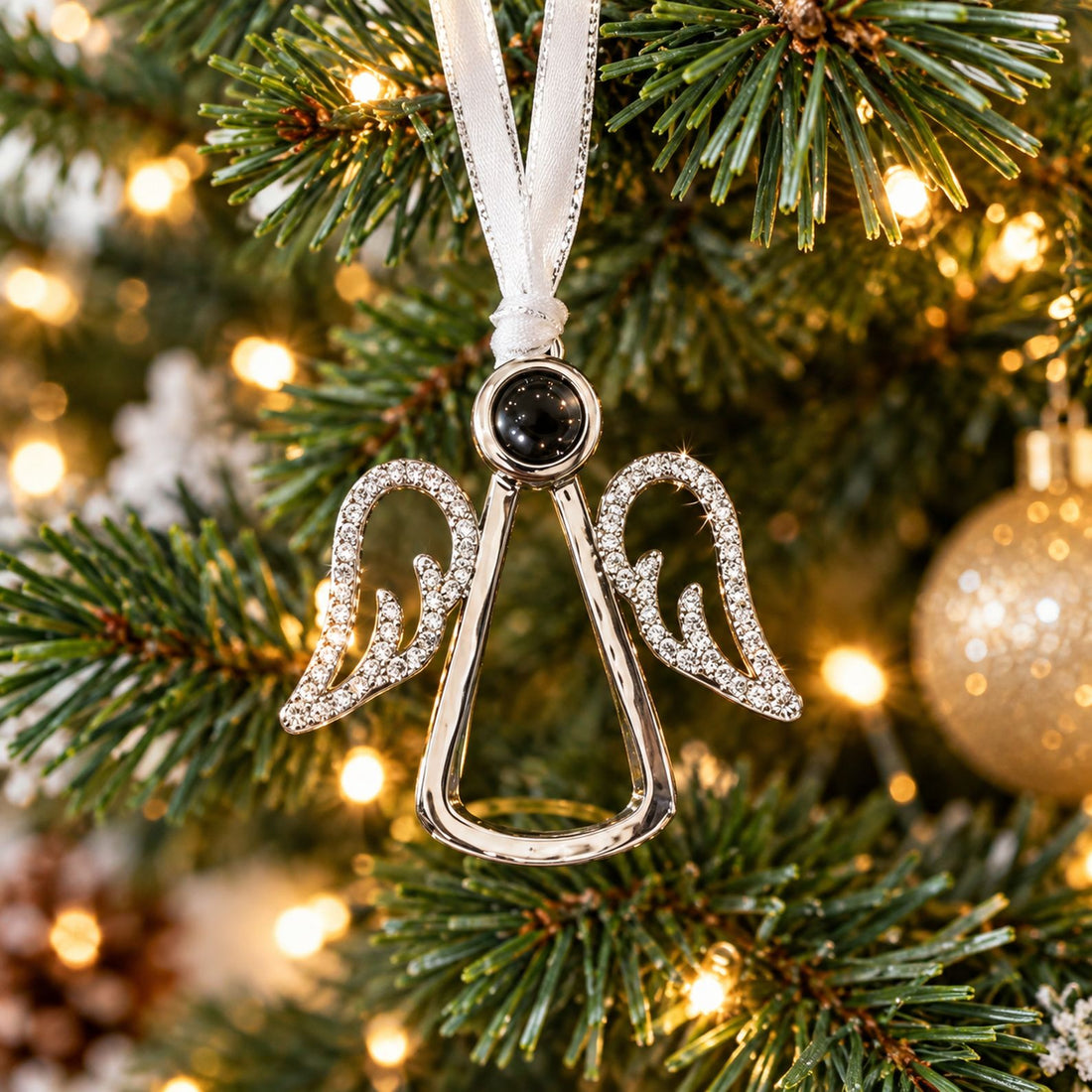 Angel wings photo projection ornament hanging on a Christmas tree branch