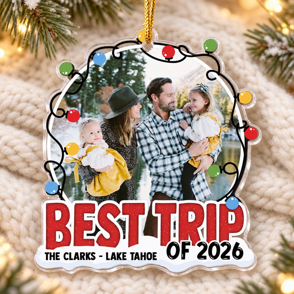 Personalized Best Trip Of 2026 acrylic family ornament lying flat on a cozy cream knit surface with pine sprigs