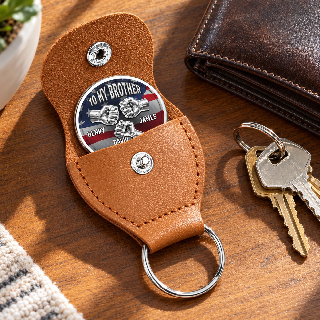 Leather pocket hug next to wallet and keys on table showing compact size