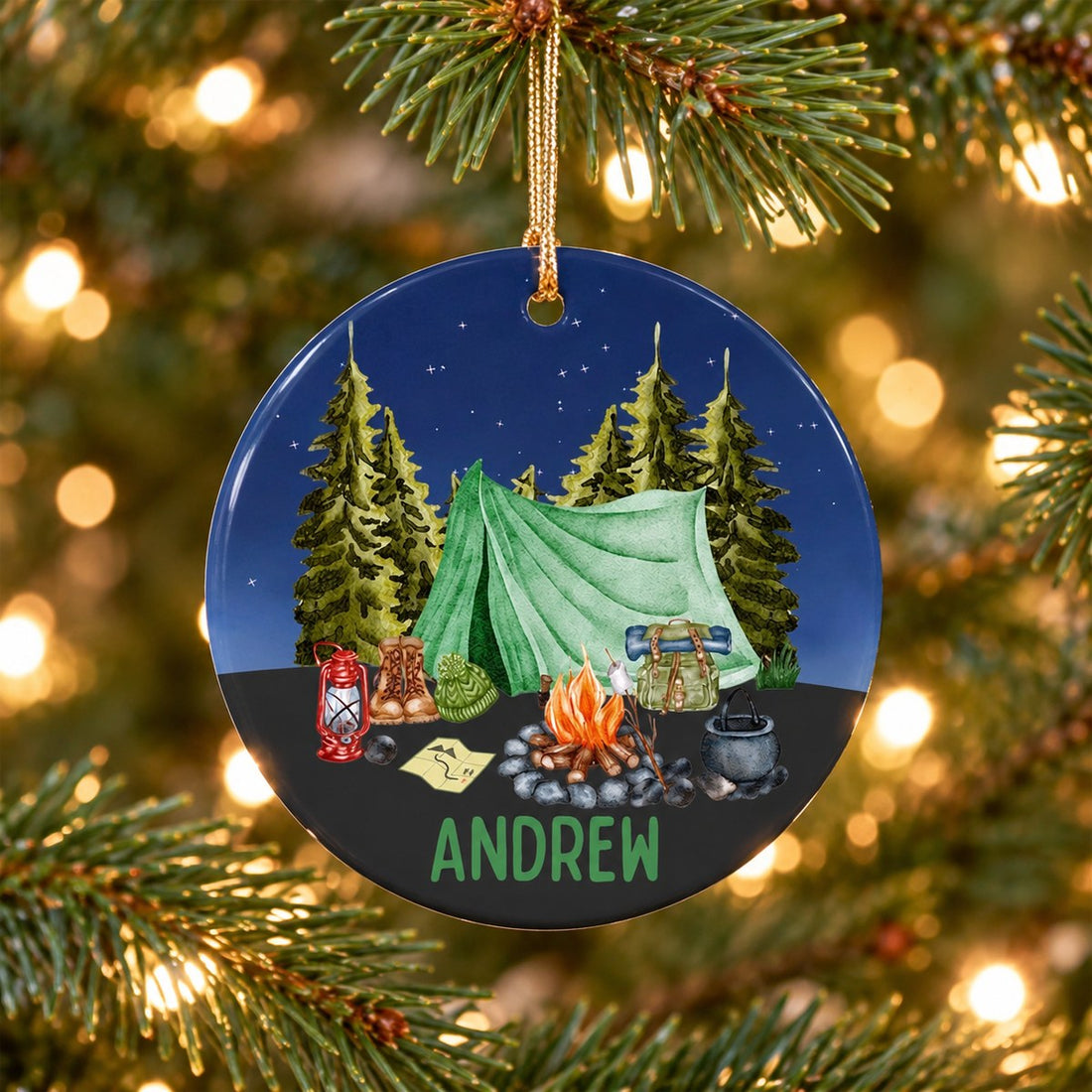 Personalized camping tent circle ceramic ornament hanging on a Christmas tree branch with warm lights