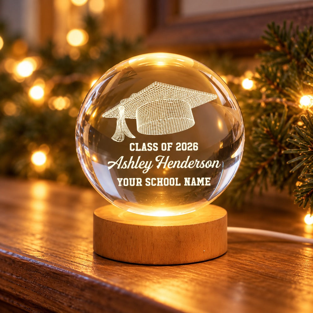 Personalized Class of 2026 graduation crystal ball LED night light glowing on a wooden mantel with soft festive lights