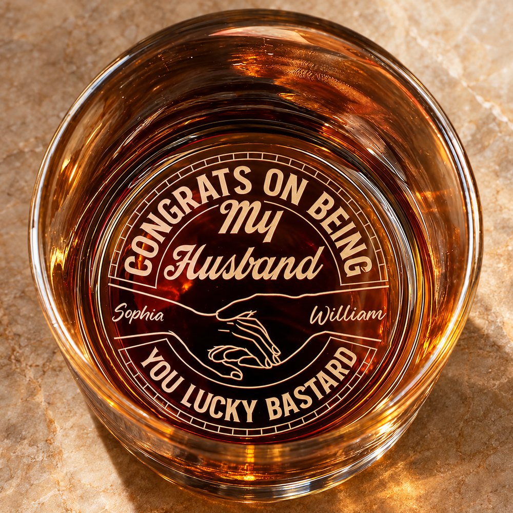 Close-up top view of engraved whiskey glass bottom showing holding hands artwork and My Husband text