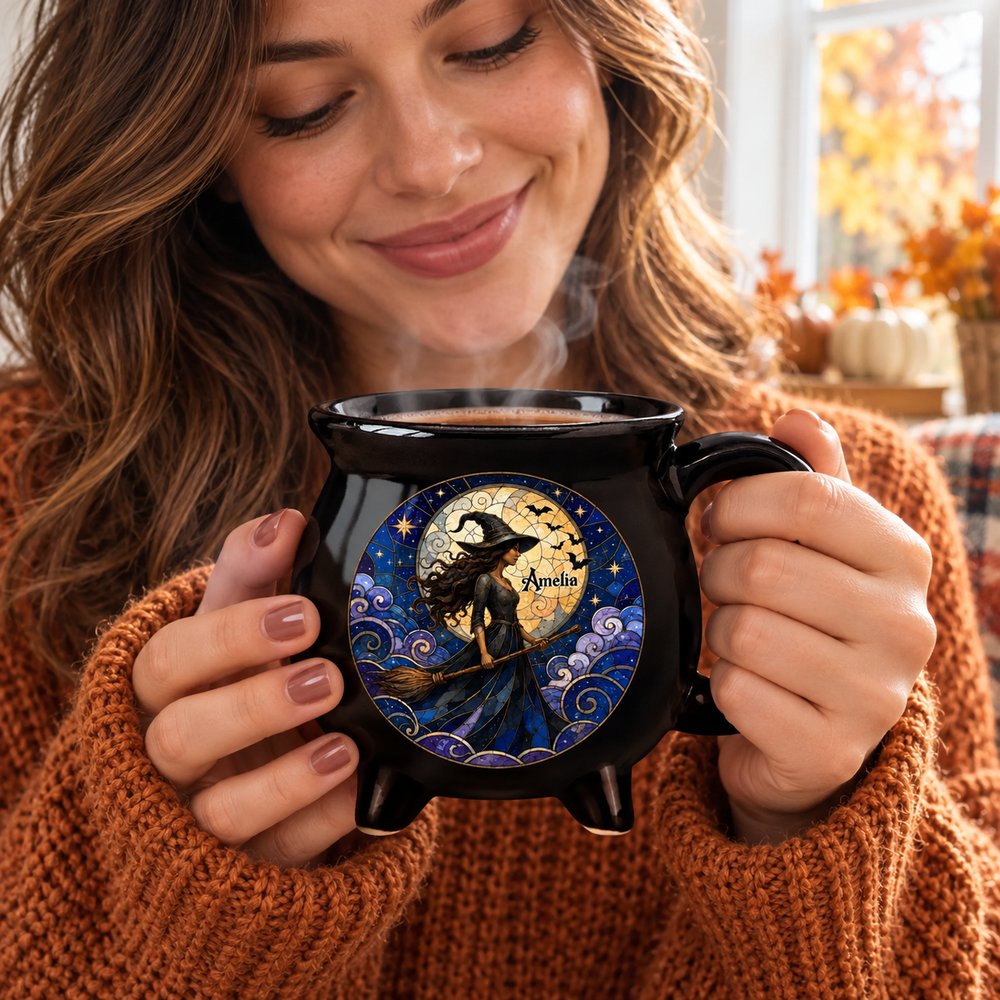 Woman holding personalized Halloween mystic witch black ceramic cauldron coffee mug in cozy autumn sweater