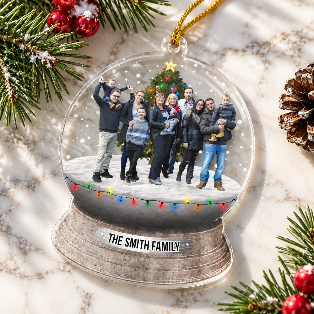 Personalized snowglobe shape acrylic ornament lying flat on a Christmas mantel with pine sprigs