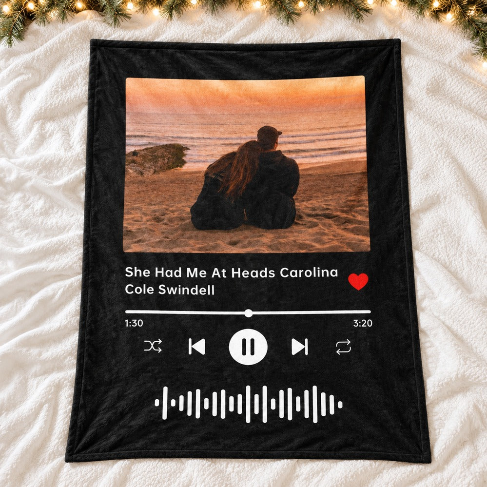 Custom wedding song photo blanket spread flat on a bed with holiday greenery and lights