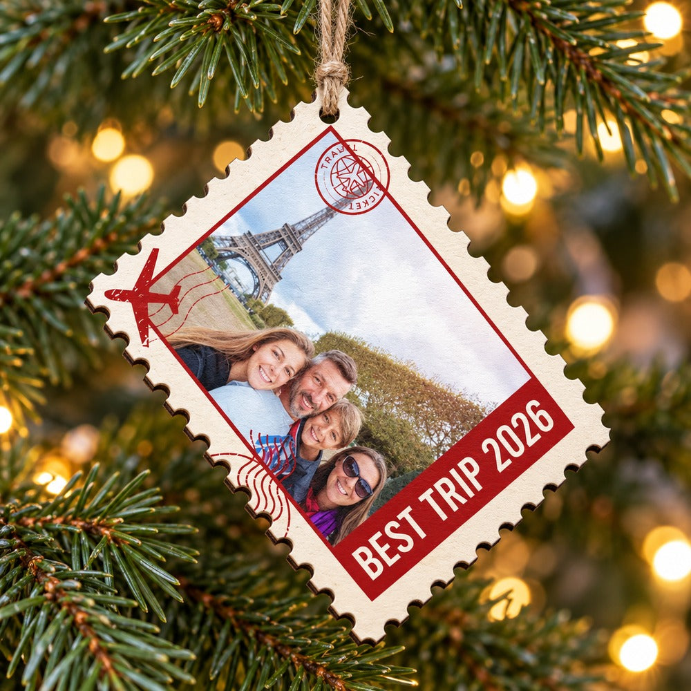 Custom photo postage stamp wood ornament BEST TRIP 2026 hanging on a bright Christmas tree branch