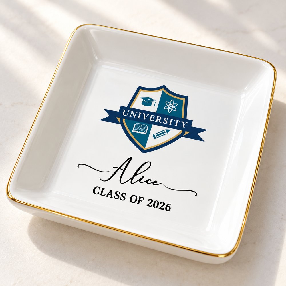 Close-up of glossy ceramic graduation jewelry dish showing gold rim and printed university crest