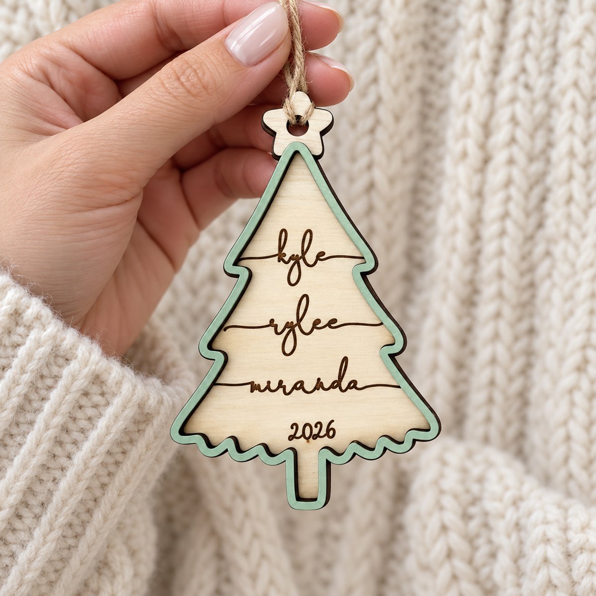 Hand holding personalized 2-layer wooden family Christmas tree ornament to show real size