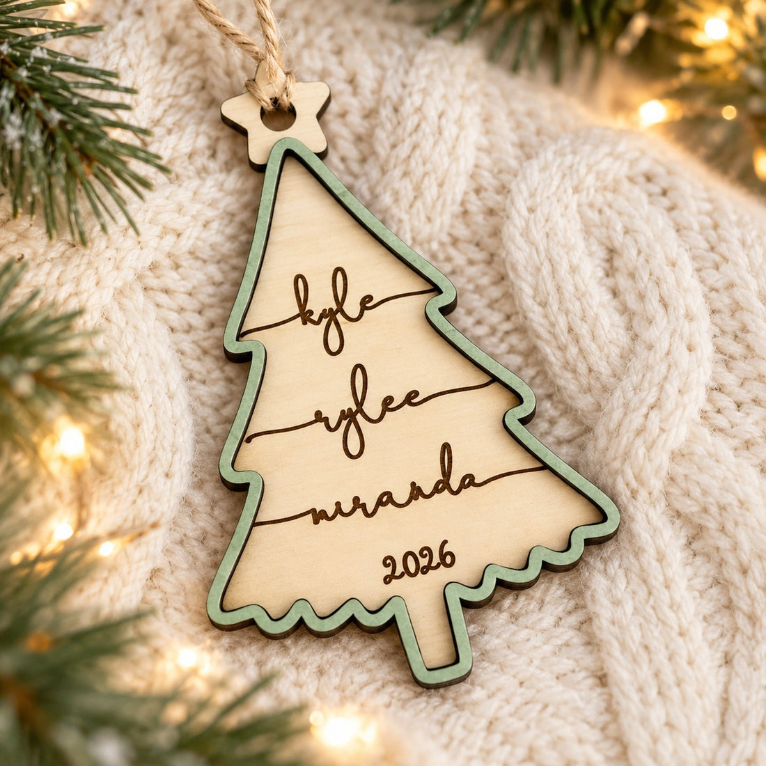 Personalized 2-layer family Christmas tree wood ornament with sage green frame on a cozy knit blanket