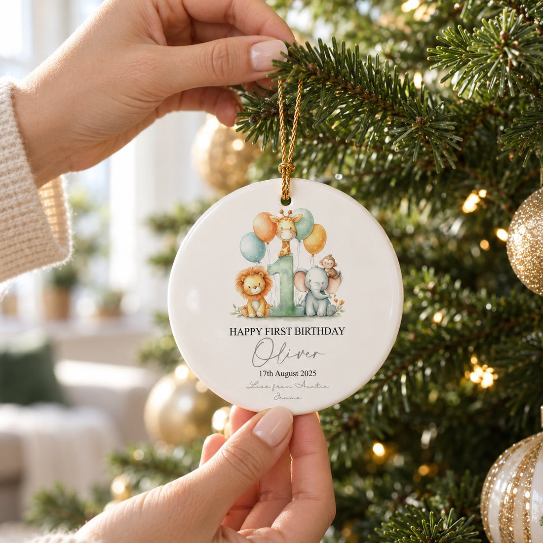 Personalized first birthday safari ceramic ornament being hung on a Christmas tree branch
