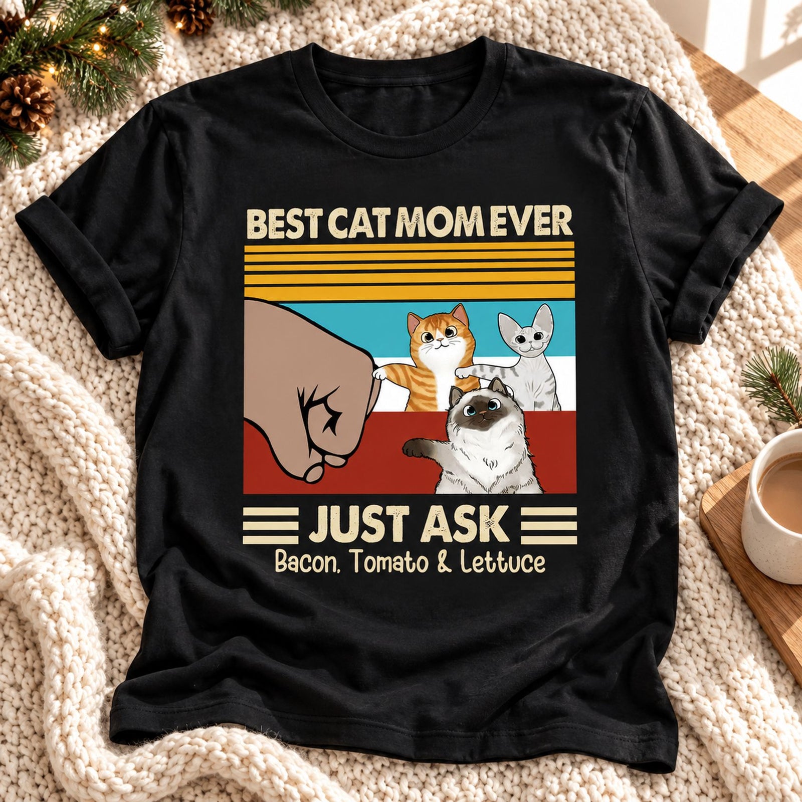 Best Cat Mom Ever personalized t-shirt laid flat on a holiday blanket with pine garland