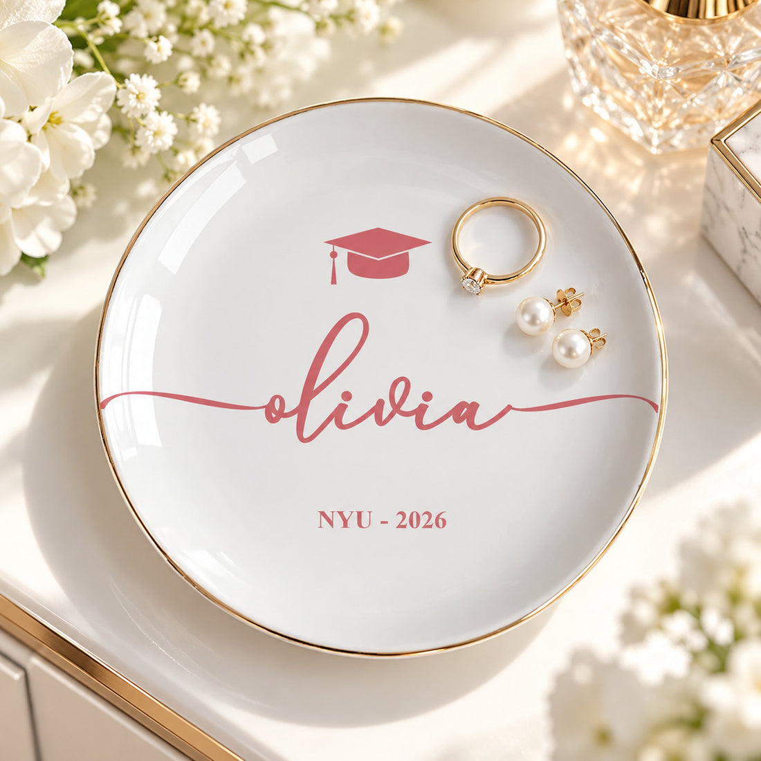Personalized graduation jewelry dish holding gold ring and pearl earrings on vanity table