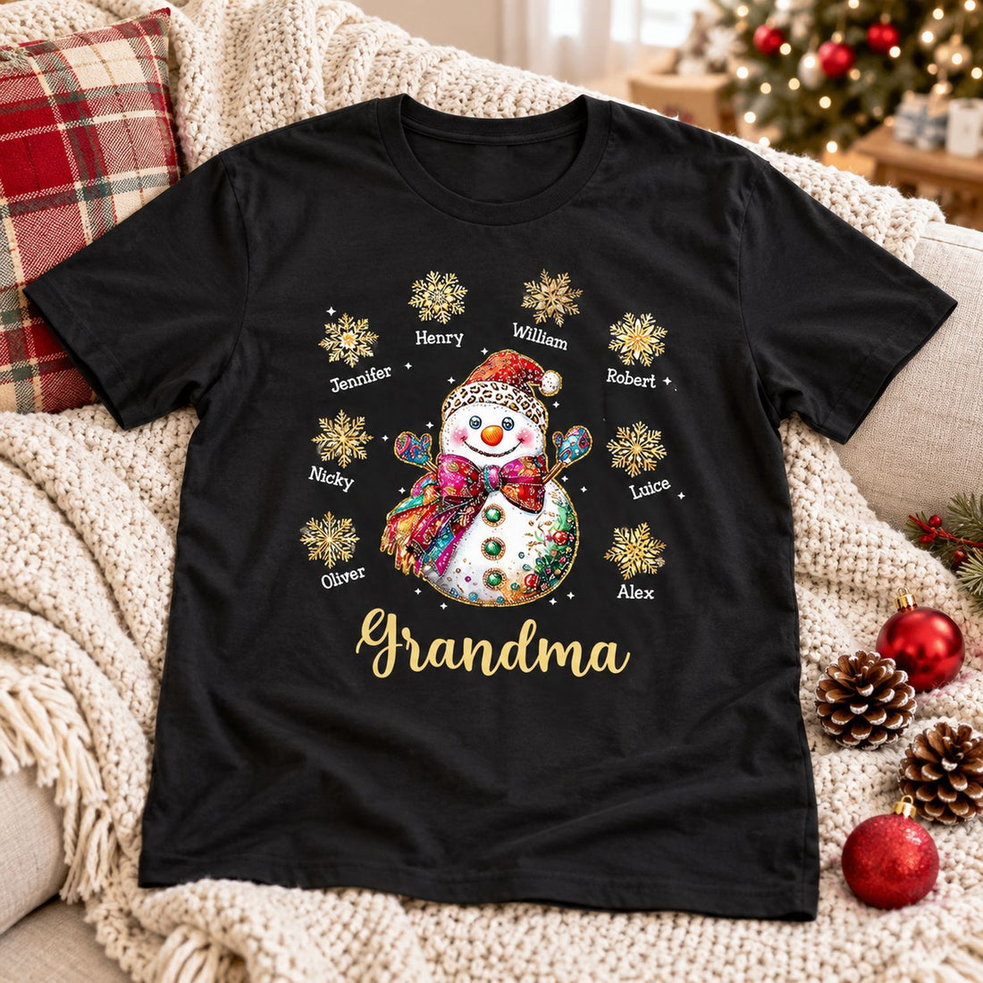 Personalized Grandma Christmas snowman black t-shirt laid on a cozy holiday sofa