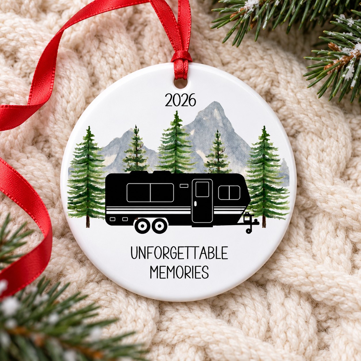 Personalized RV camping ceramic ornament lying flat on a cream knit blanket with festive greenery