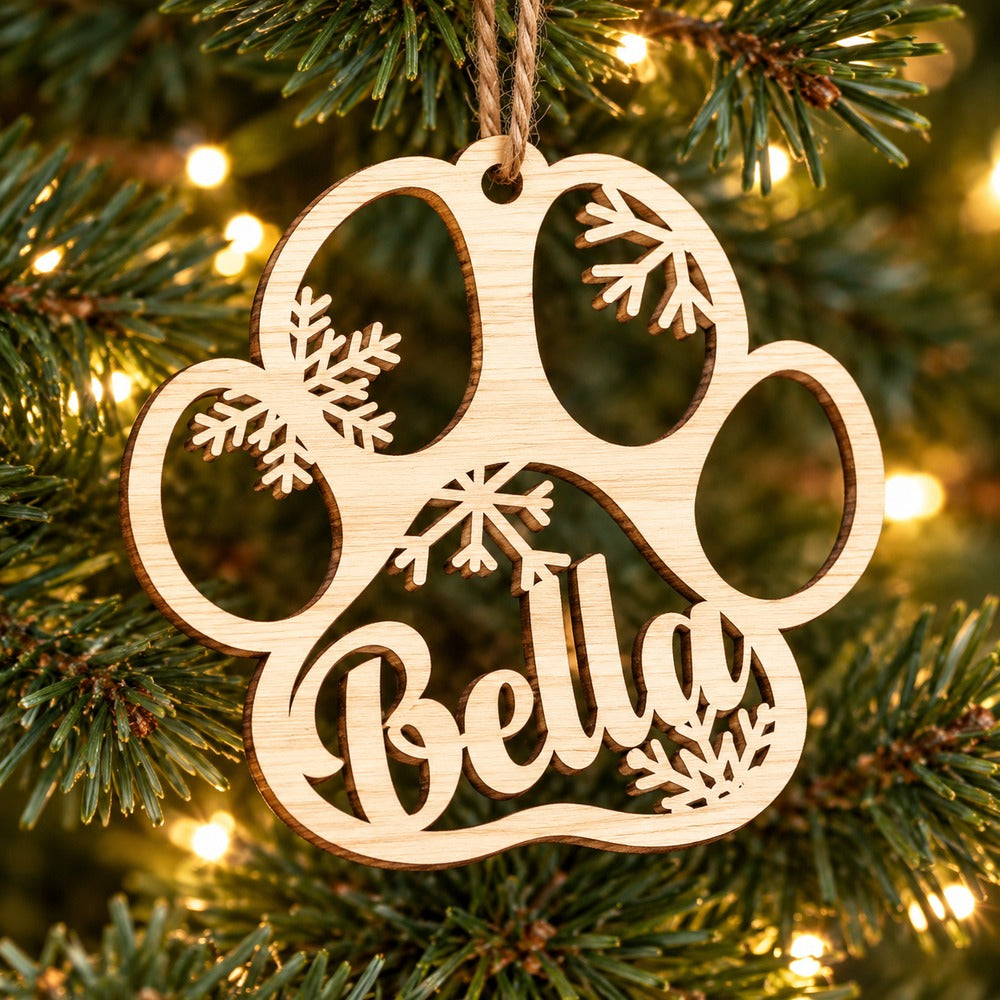 Personalized Bella wooden dog paw ornament hanging on a Christmas tree branch