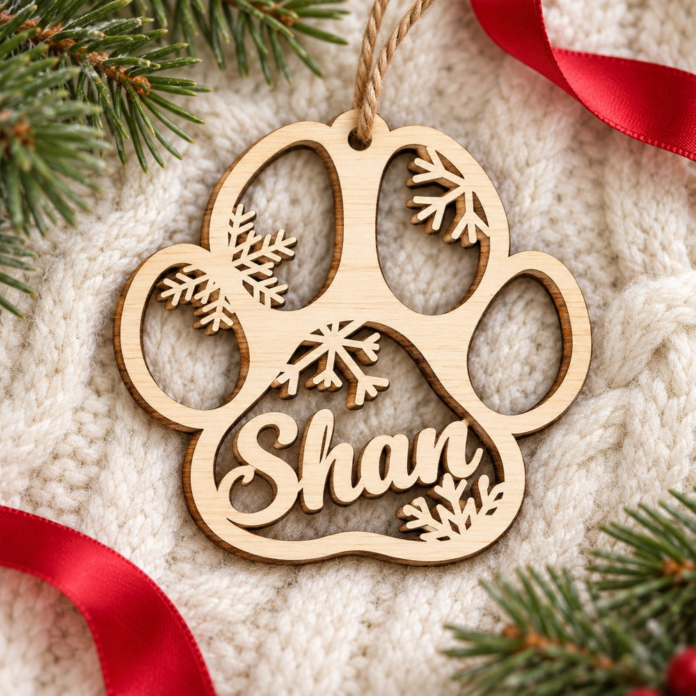 Custom Shan wooden paw print Christmas ornament lying on a cozy cream knit throw
