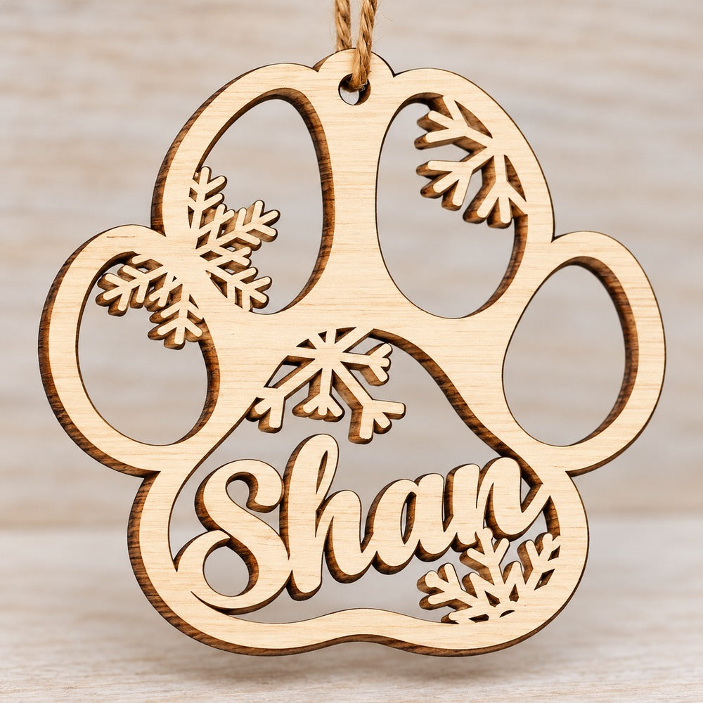 Macro close-up of laser-cut wooden paw ornament showing wood grain and snowflake details