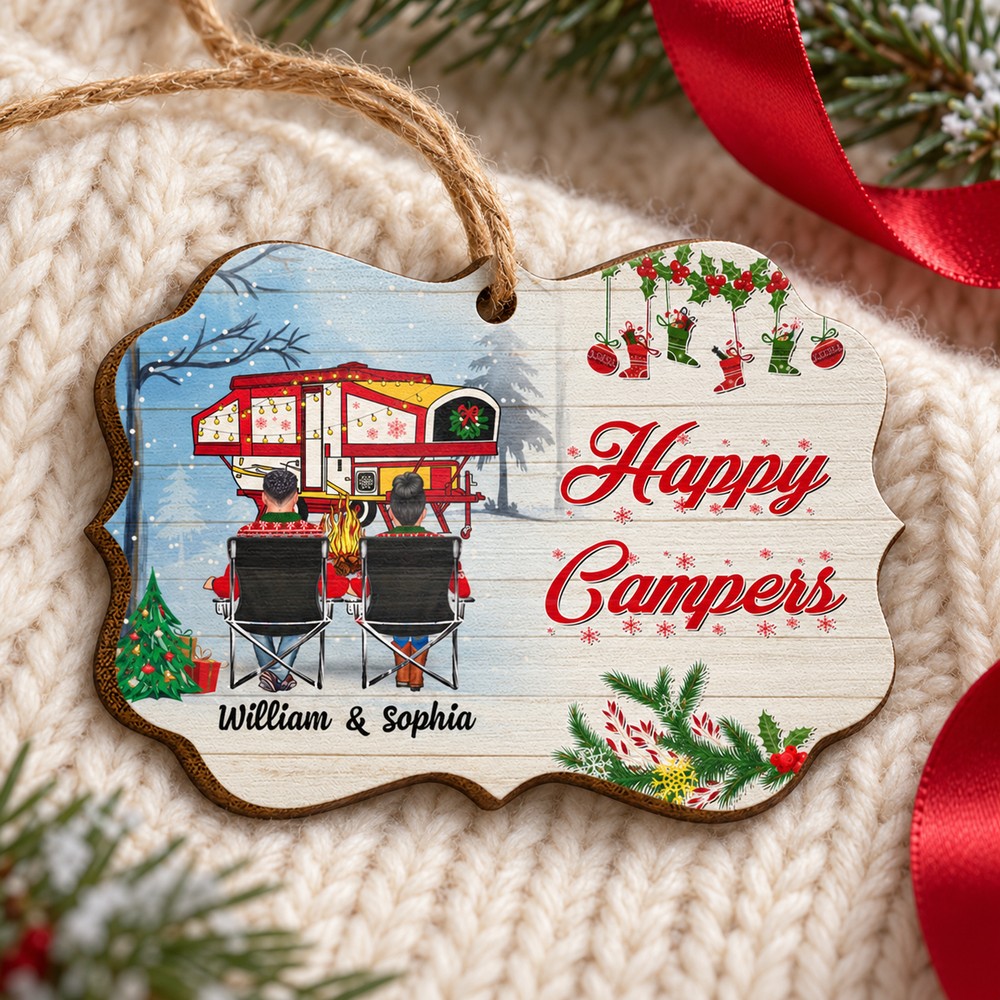Happy Campers personalized wooden ornament lying flat on cream knit fabric with pine greenery