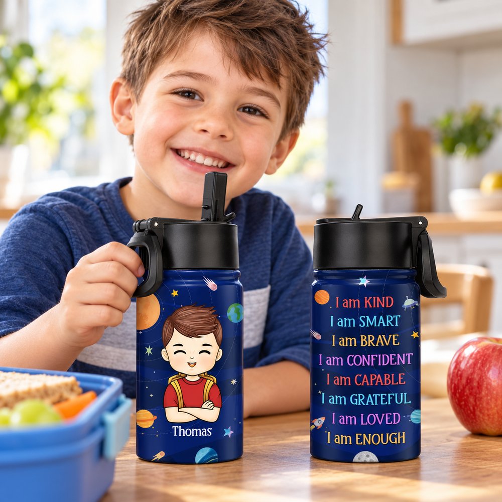 Young boy holding personalized 12oz kids space water bottle at kitchen table