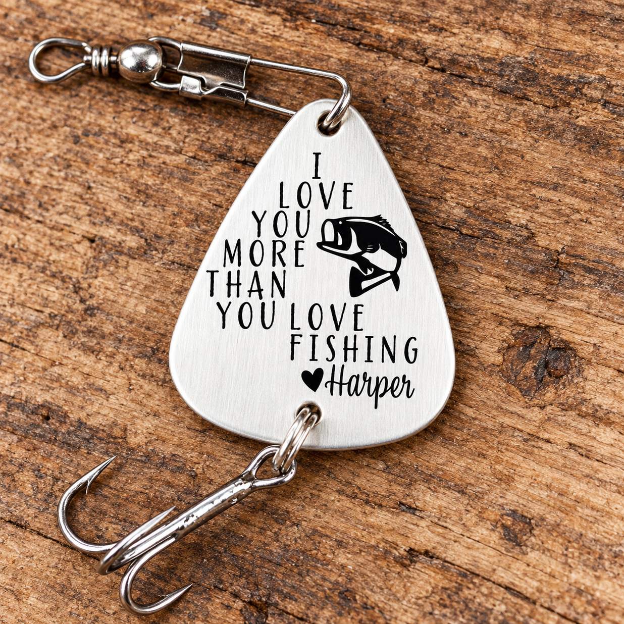Macro close-up of personalized engraved silver metal fishing lure showing bass graphic and Harper engraving