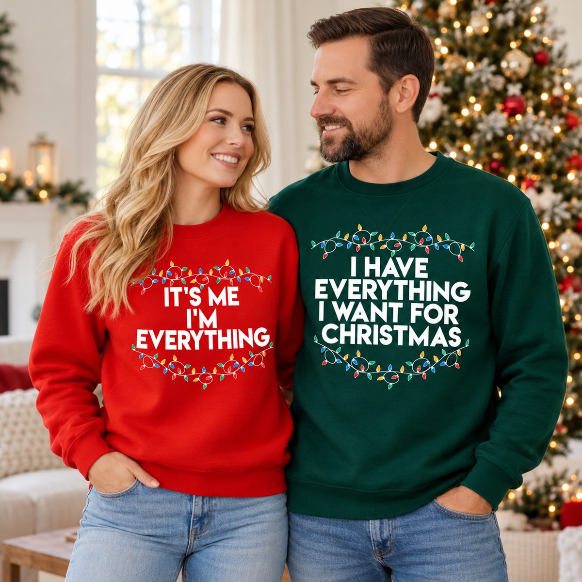 Couple wearing matching red and green I Have Everything I Want For Christmas sweatshirts by tree