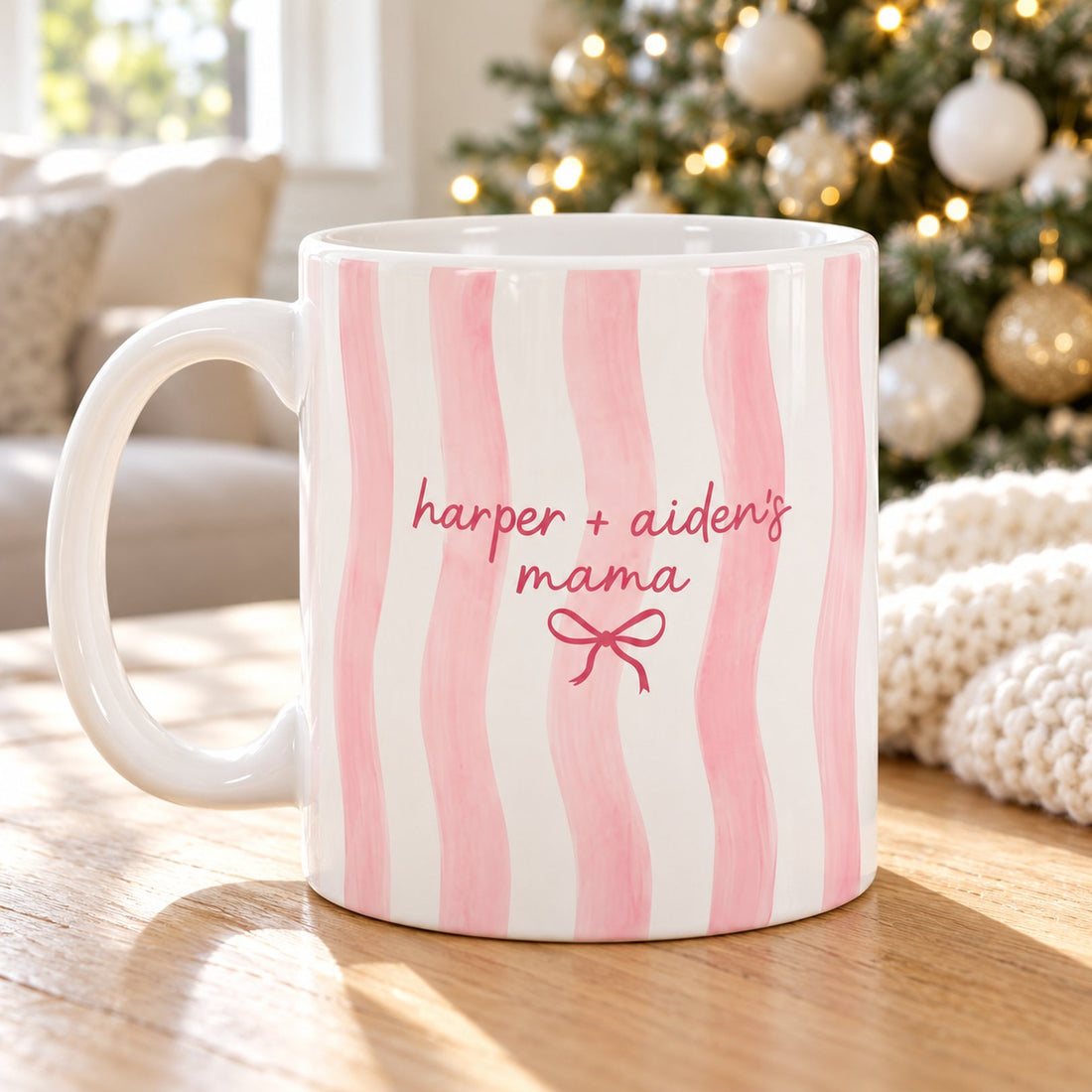 Personalized pink striped Mama mug on a table near a softly blurred Christmas tree
