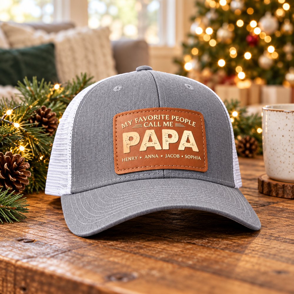 Personalized Papa leather patch trucker hat on wooden table in front of a Christmas tree