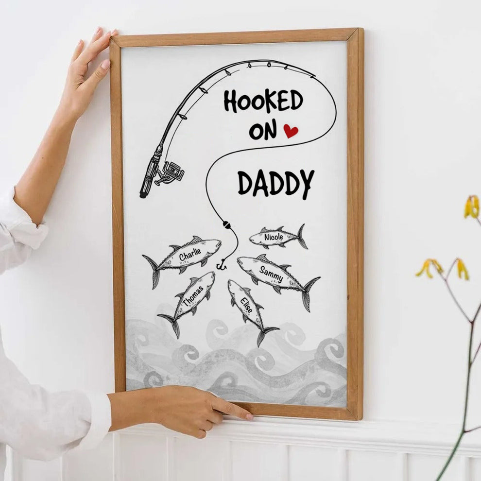 Personalized Fishes Hooked On Daddy Grandpa poster, leaning against a wall on a wooden floor