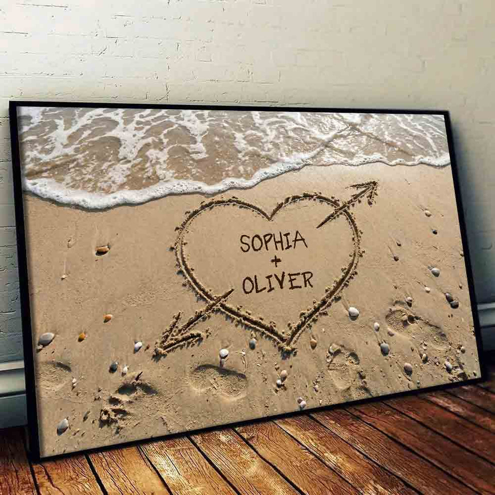 Personalized Couple Names Heart in Sand canvas print, leaning against a wall on a wooden floor