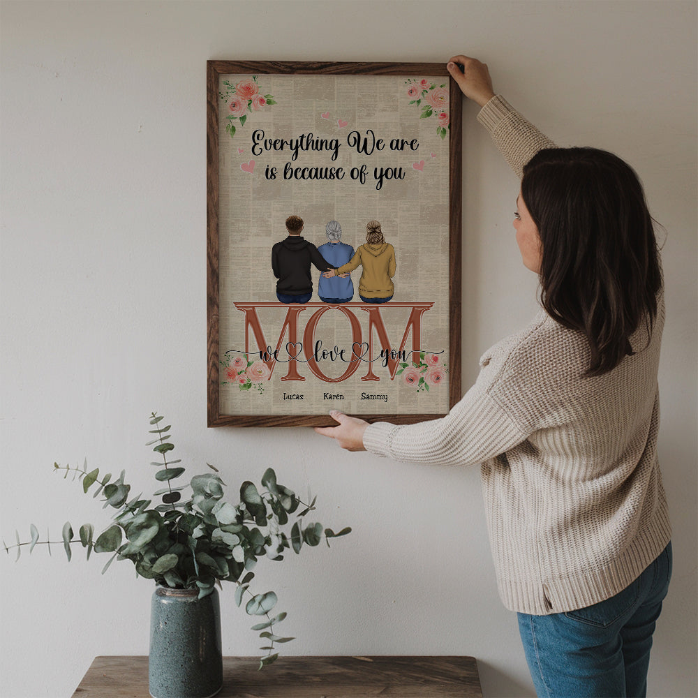 Mom's Personalized Canvas Print: "Everything We Are" Custom Character poster, a woman hanging the framed print on a wall