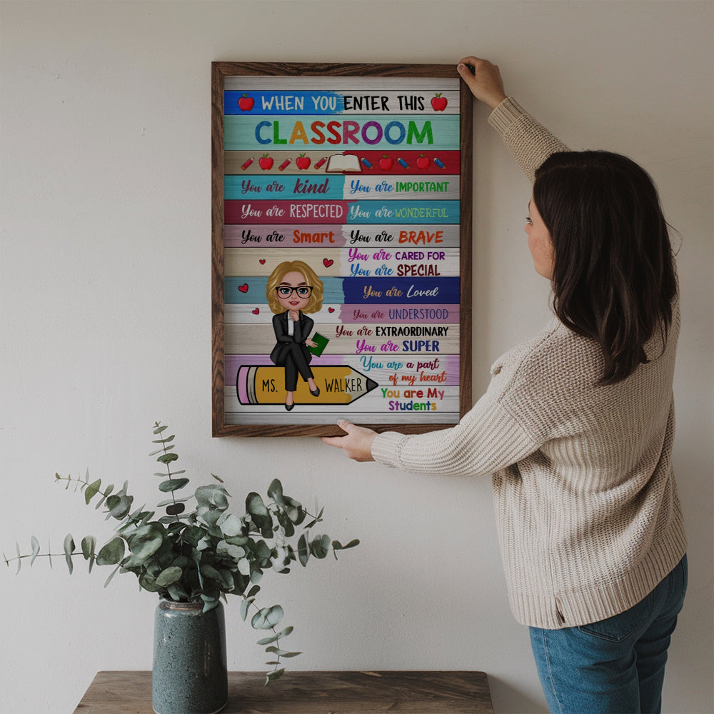 Personalized Colorful Teacher Sitting On Pencil poster, a woman hanging the framed print on a wall