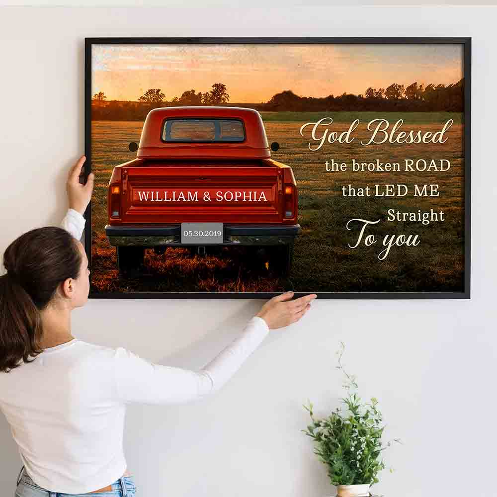 Personalized God Blessed The Broken Road Couple poster, a woman hanging the framed print on a wall