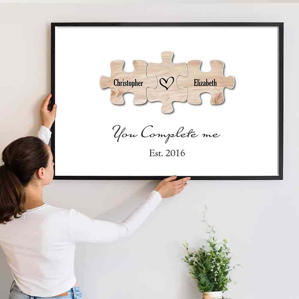 Personalized You Complete Me Couple Puzzle canvas print, a woman hanging the framed print on a wall