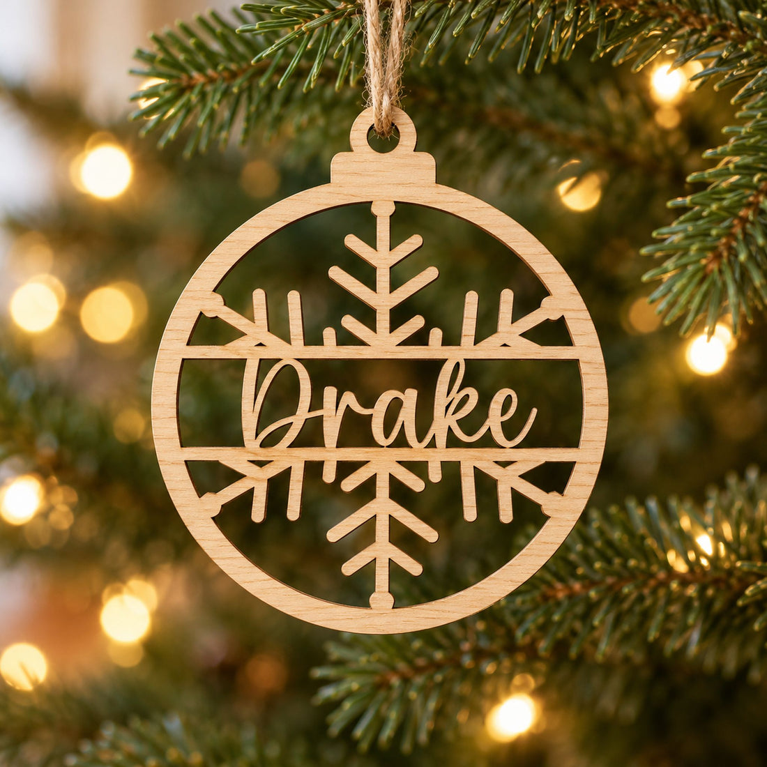 Personalized name laser-cut wood ornament hanging on a green Christmas tree branch