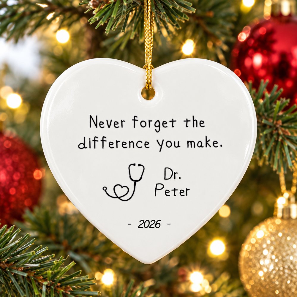 Personalized nurse heart ceramic ornament hanging on a Christmas tree branch with warm lights