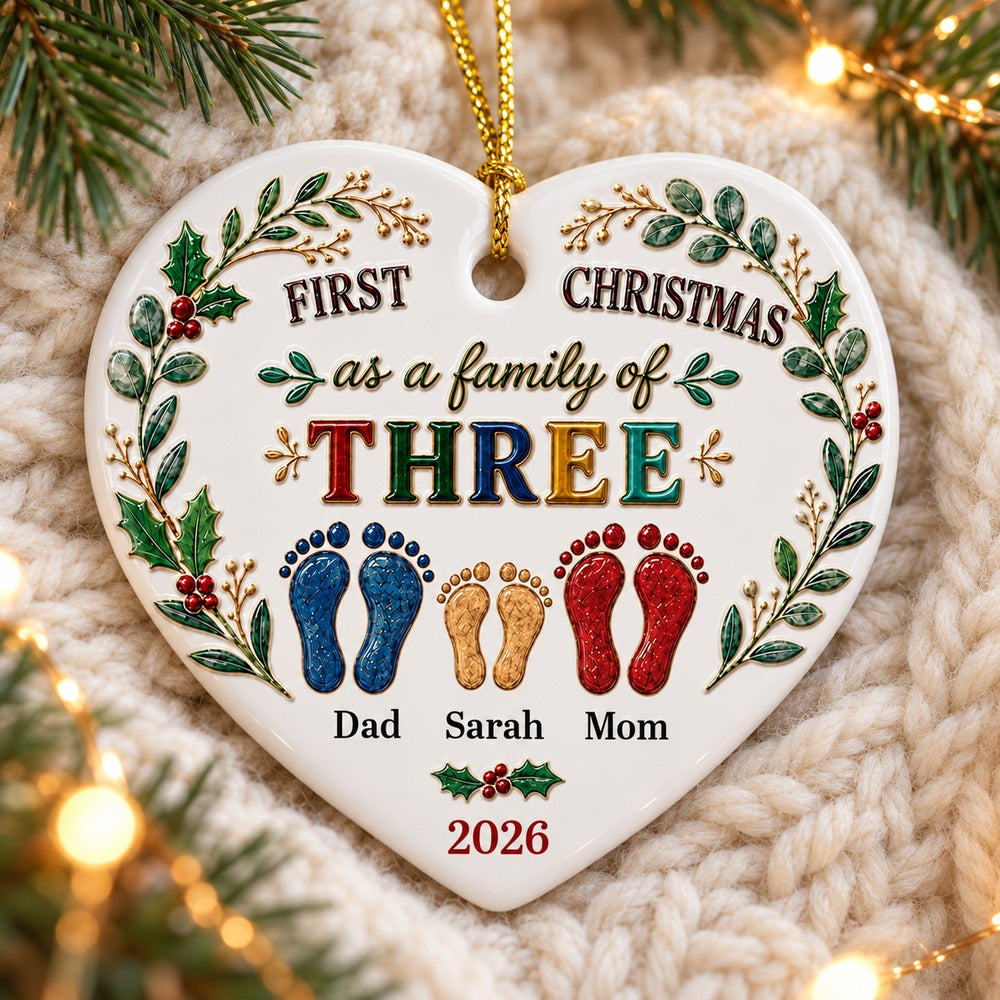 Personalized heart ceramic ornament for family of three lying flat on a cream knit blanket with pine greenery