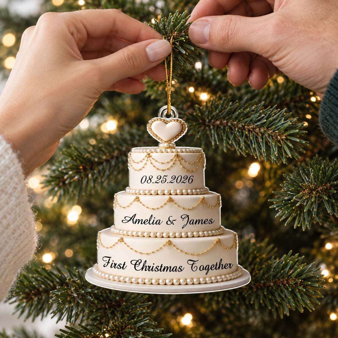 Personalized wedding cake acrylic ornament being hung on a Christmas tree by a couple
