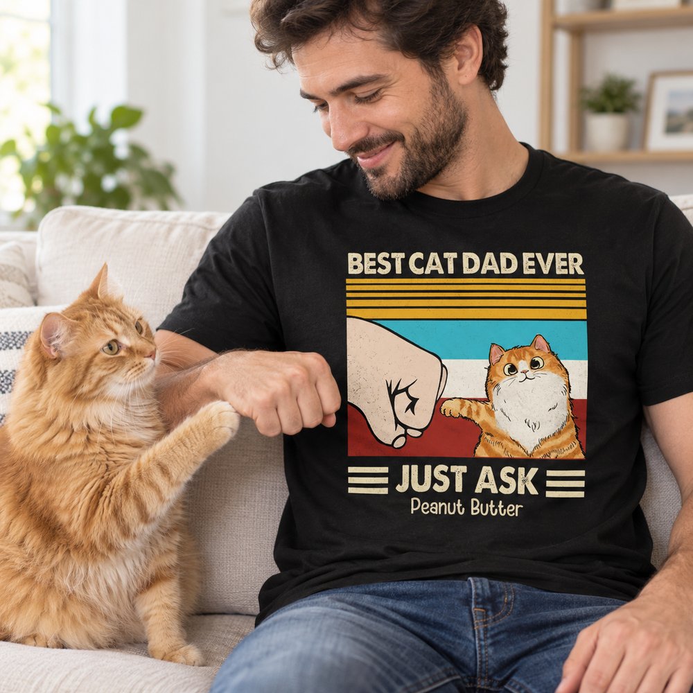 Man wearing Best Cat Dad Ever custom t-shirt sitting on a sofa with his ginger cat