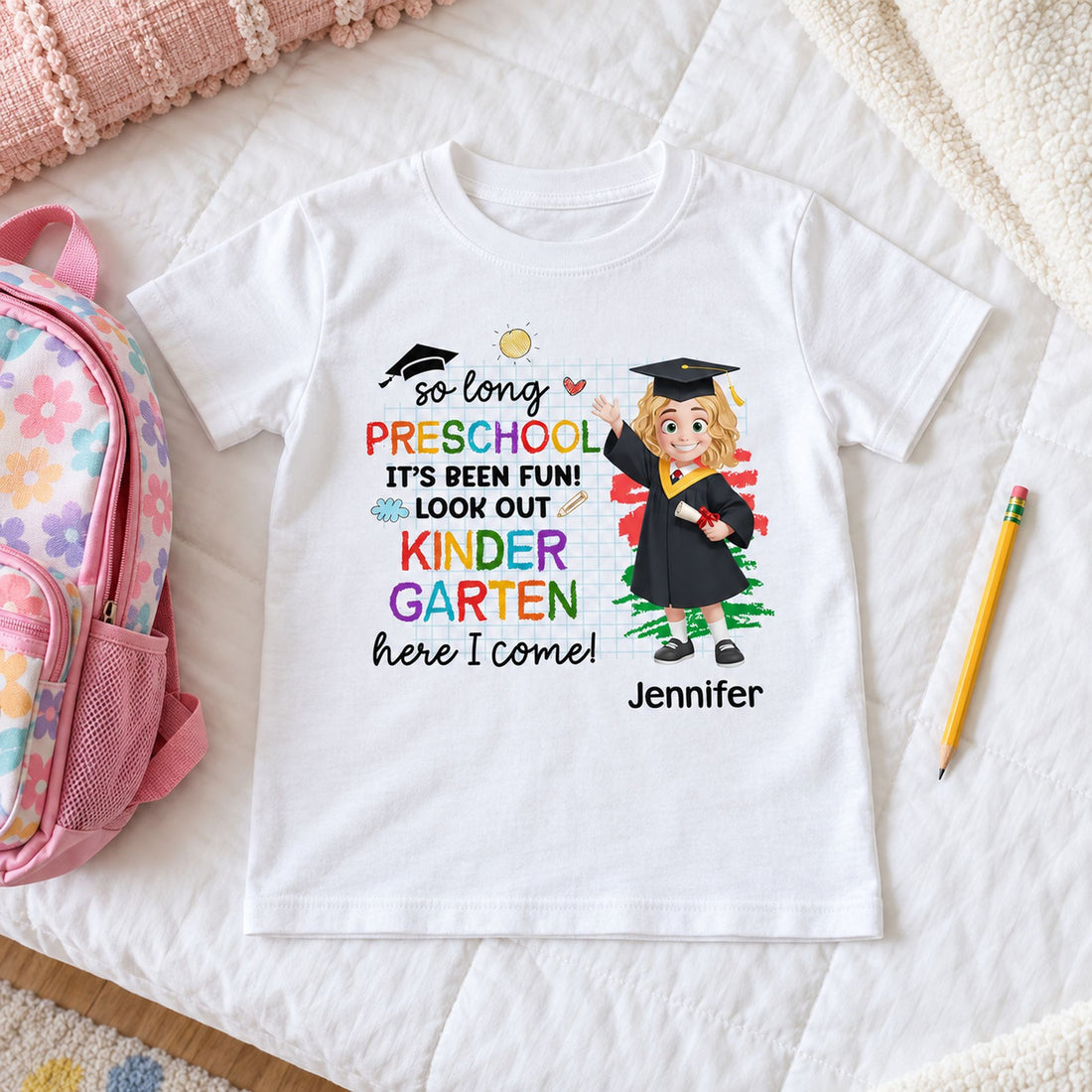 Youth size Pre-K graduation shirt laid next to a kid backpack to show real scale