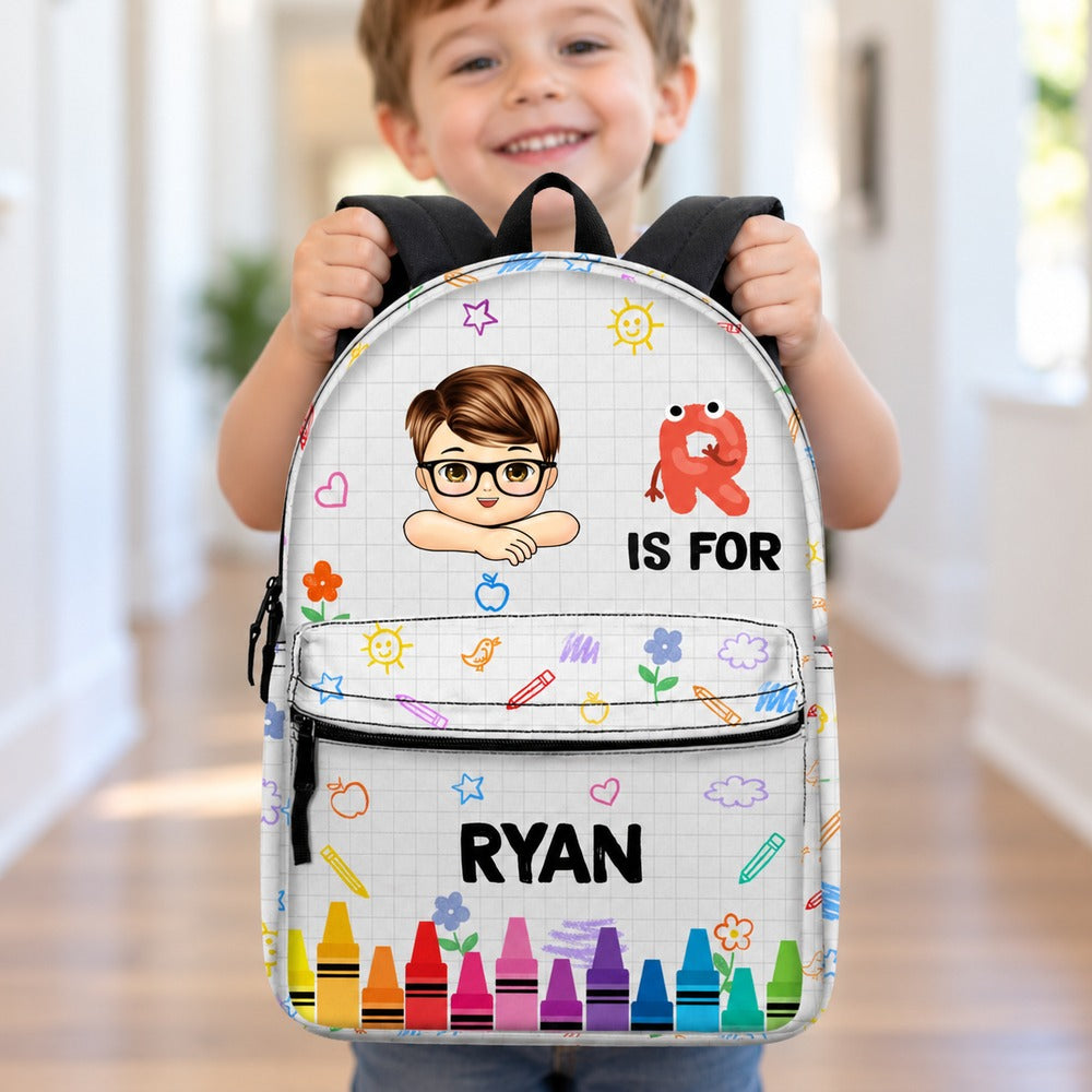 Preschool boy holding his personalized Ryan school backpack with crayon design
